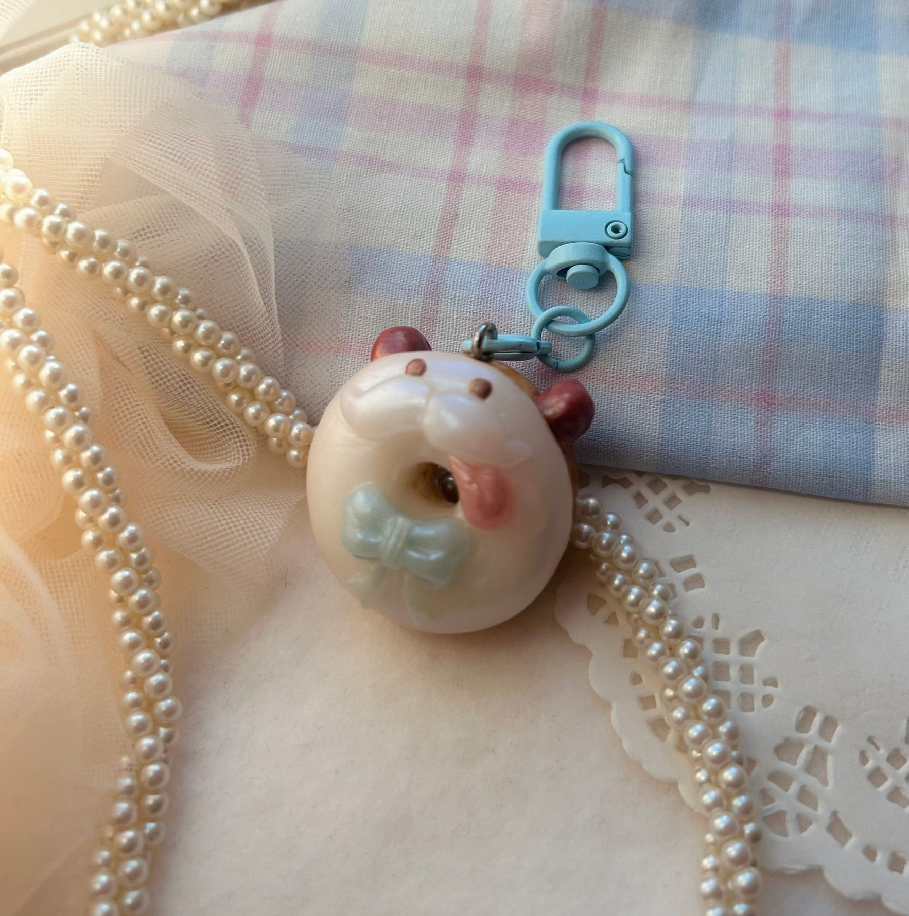 Donut-shaped Poro keychain with a bow on a textured fabric background